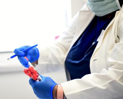 Masked doctor holding medical vials with gloved hands