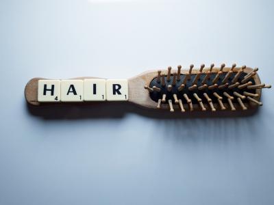 A photo of a hair brush with the word hair spelled out in scabble tiles.