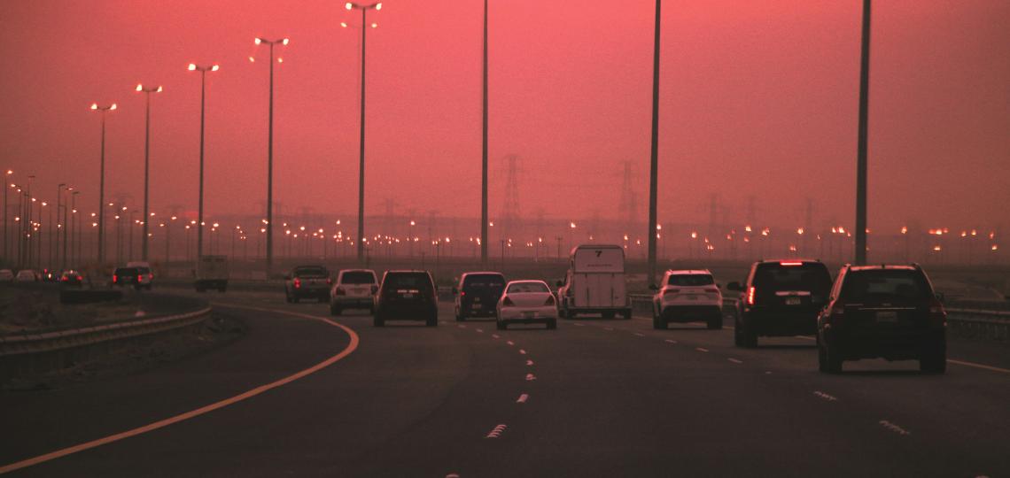Cars driving on highway with hazy polluted skies in background