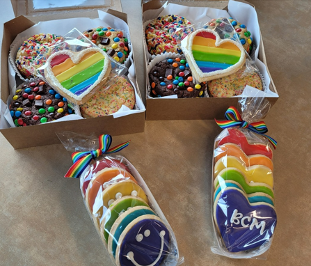 To celebrate PRIDE month, faculty and staff pose with sweet treats they plan to eat from Michael's Cookie Jar.