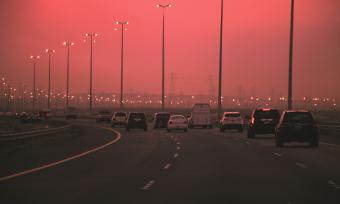 Cars driving on highway with hazy polluted skies in background
