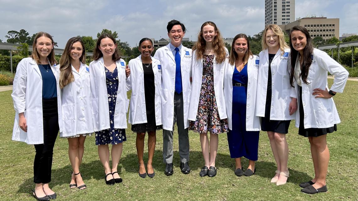 The Baylor Medicine-Pediatrics Class of 2027 stand in their white coats on a grassy field