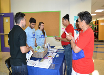 A group of people standing around a table reading program literature.