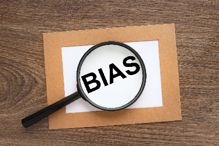 Magnifying glass over the word Bias printed on a piece of paper. 