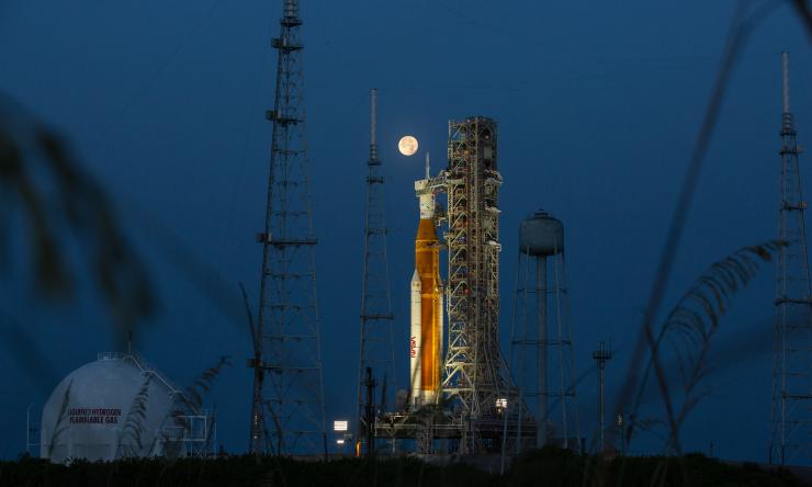 A full Moon is in view from Launch Complex 39B at NASA’s Kennedy Space Center in Florida on June 14, 2022. The Artemis I Space Launch System (SLS) and Orion spacecraft, atop the mobile launcher, are being prepared for a wet dress rehearsal to practice timelines and procedures for launch. The first in an increasingly complex series of missions, Artemis I will test SLS and Orion as an integrated system prior to crewed flights to the Moon. Through Artemis, NASA will land the first woman and first person of col