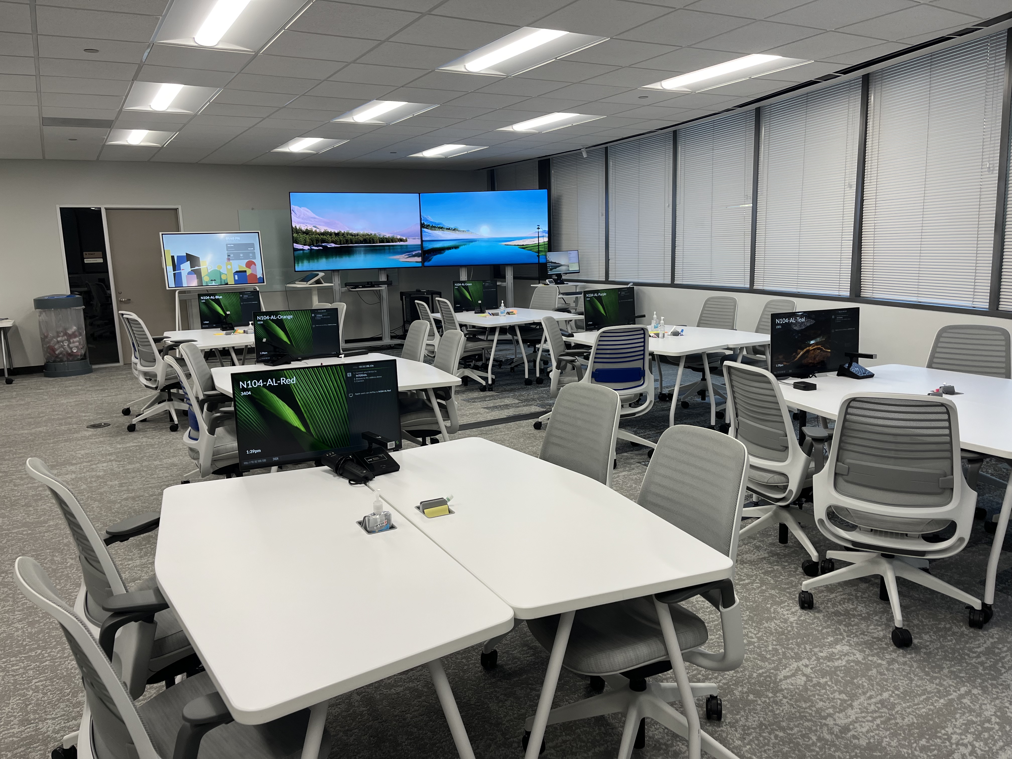 classroom with desks, screens, and a digital whiteboard