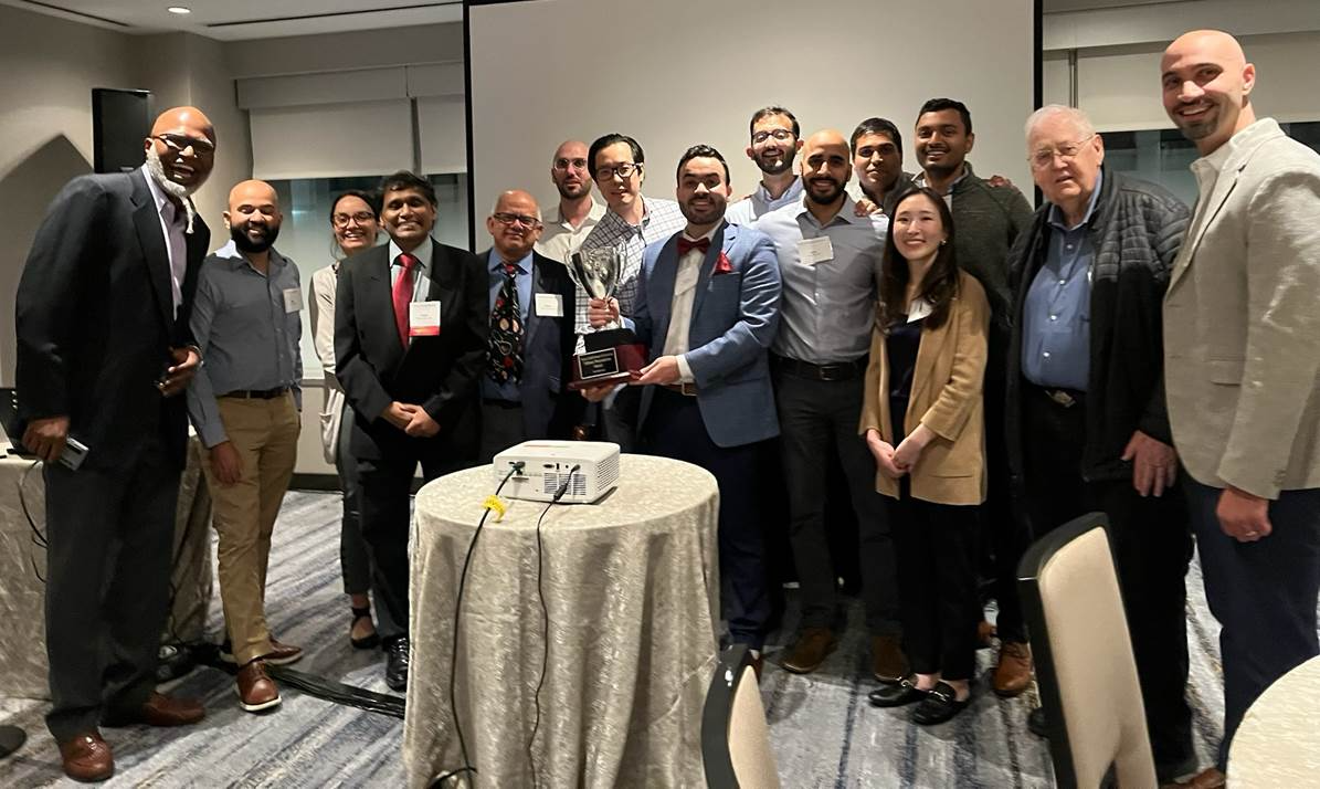 group of people smiling with one holding an award