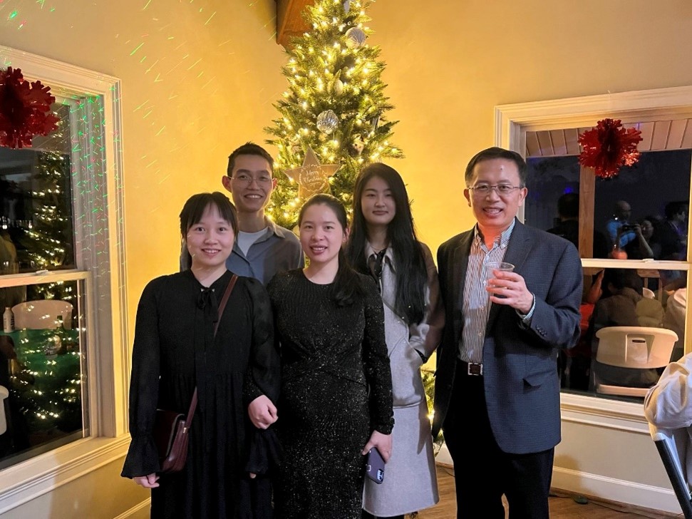 group of people standing in front of a Christmas tree