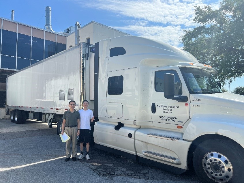 two men standing next to a white 19-wheel semi truck