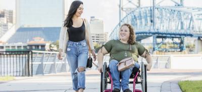 Two women enjoying a bright day on a boardwalk.