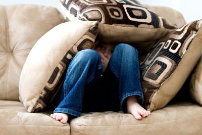 little boy hiding under pillows