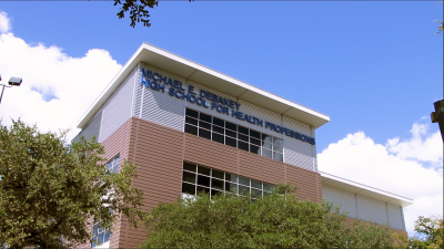 Photograph of the exterior of the DeBakey High School for Health Professions with a blue sky and clouds in the background and trees in the foreground.