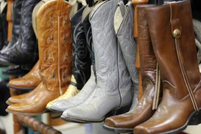 Photograph of brown and grey cowboy boots lined up on display shelf.