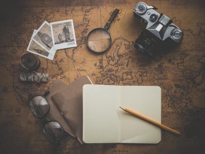 photo oa a camera, photos, glasses, notebook on a brown colored map