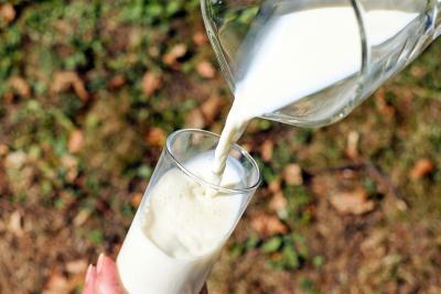 Photo of milk being poured from a glass pitcher to a glass cup.