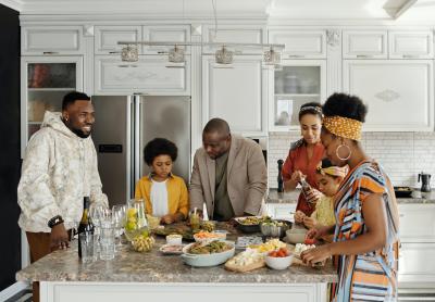 Photo of a family surrounding a kitchen island covered in food. 