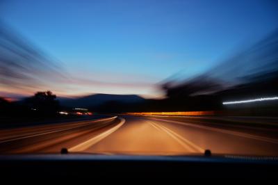 Photo taken at night from the drivers seat of a car of the road with blurred edges to signify driving and movement.