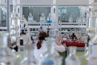 Photo of a woman taken from behind of her working in a lab. 