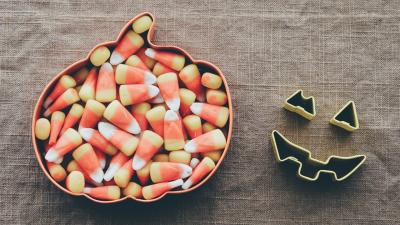 Photo of candy corn in a bowl shaped like an pumpkin. 