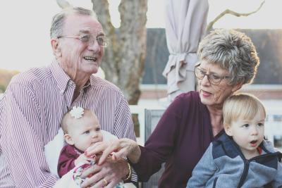 A photo of an elderly couple holding their young grandchildren