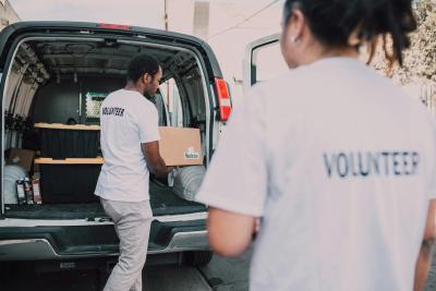 Photograph of volunteers loading a van with boxes of donations. 