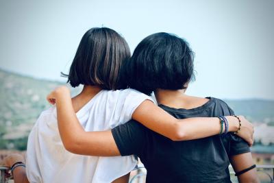 A photo taken from behind of two girls hugging, supporting each other during a difficult time. 