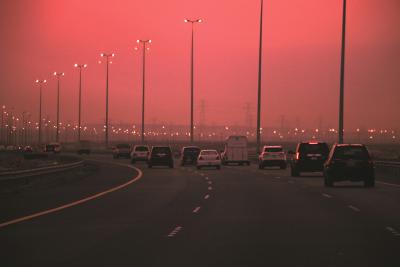 Cars driving on highway with hazy polluted skies in background