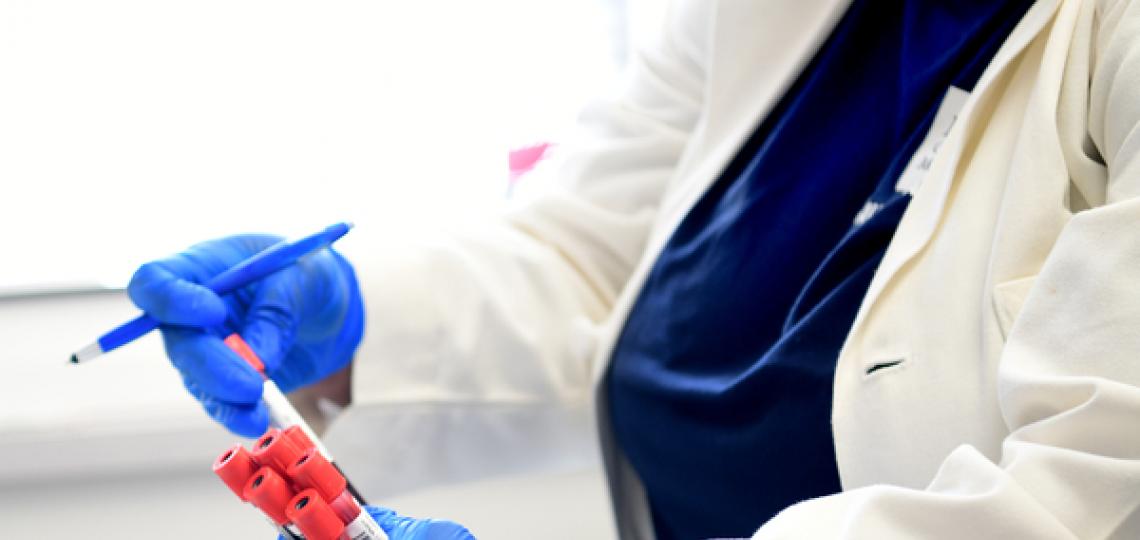 Masked doctor holding medical vials with gloved hands