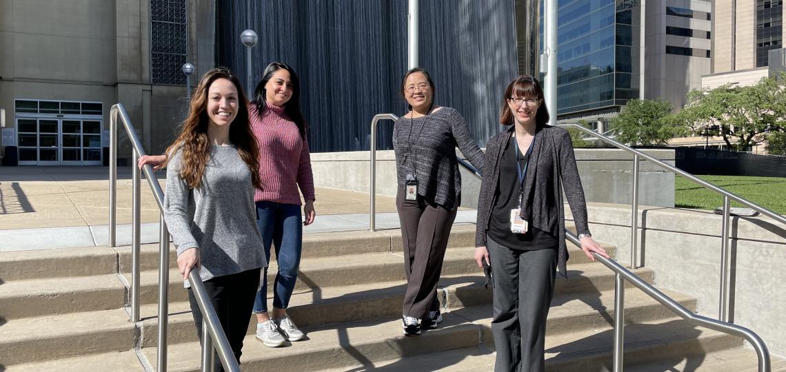 Four women standing on a set of stairs on a sunny day.