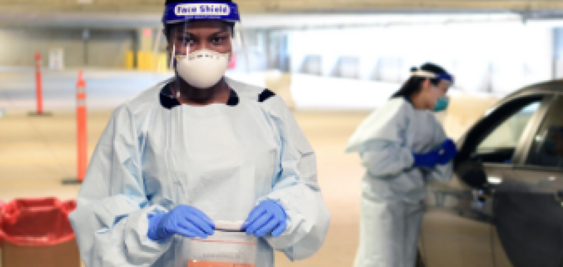 Masked healthcare worker collecting COVID test sample.