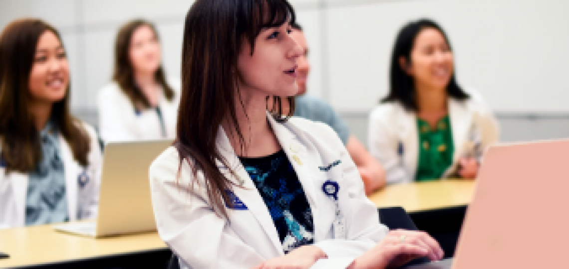 Female student sitting in front of a computer and participating in a lecture.