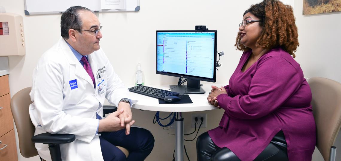 A doctor and her patient are sitting and discussing care and treatment in front of a computer. 
