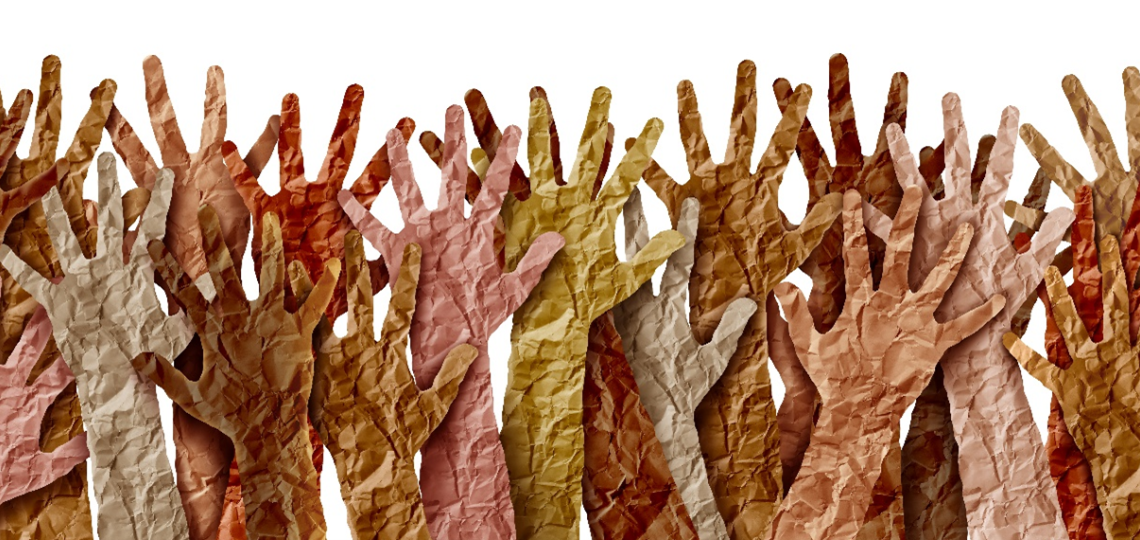 Hands cut out of paper in a raised position - representing many races of humans.