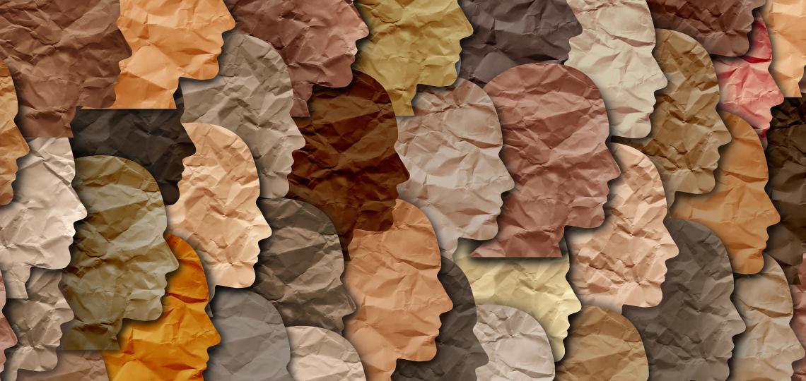 Paper cut out images of multi-colored faces representing diversity.