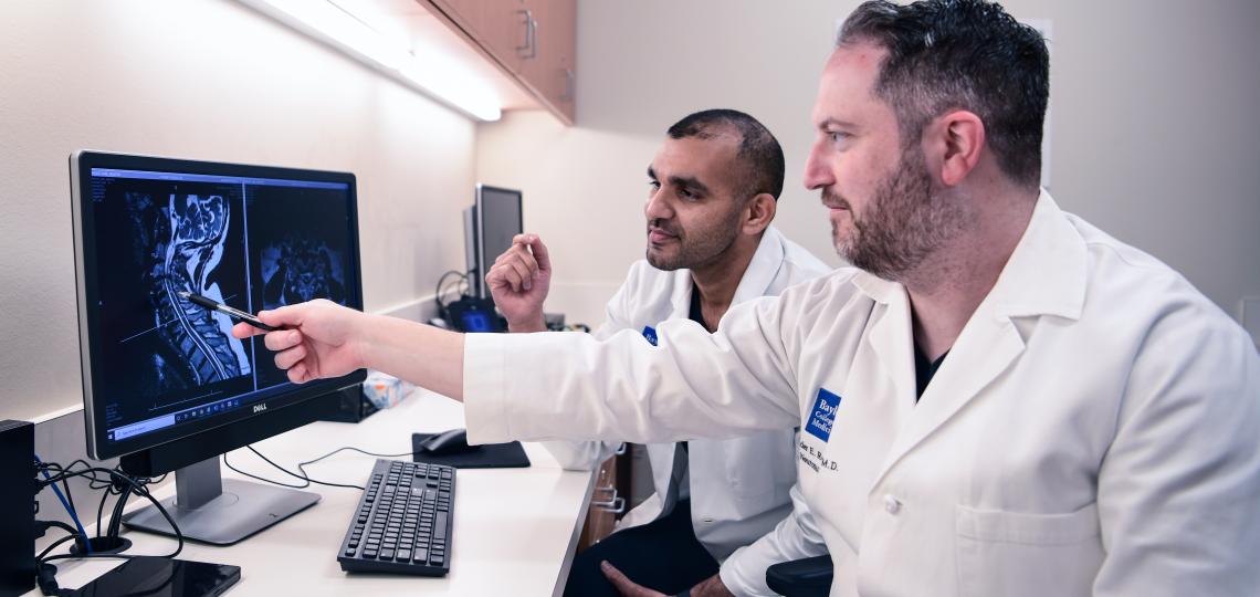 Two male doctors observing the image of a spine x-ray.