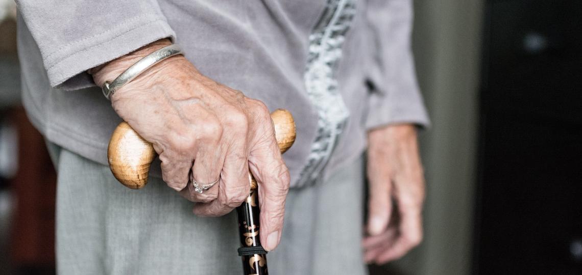 Close up photo of an elderly woman's hands holding a cane