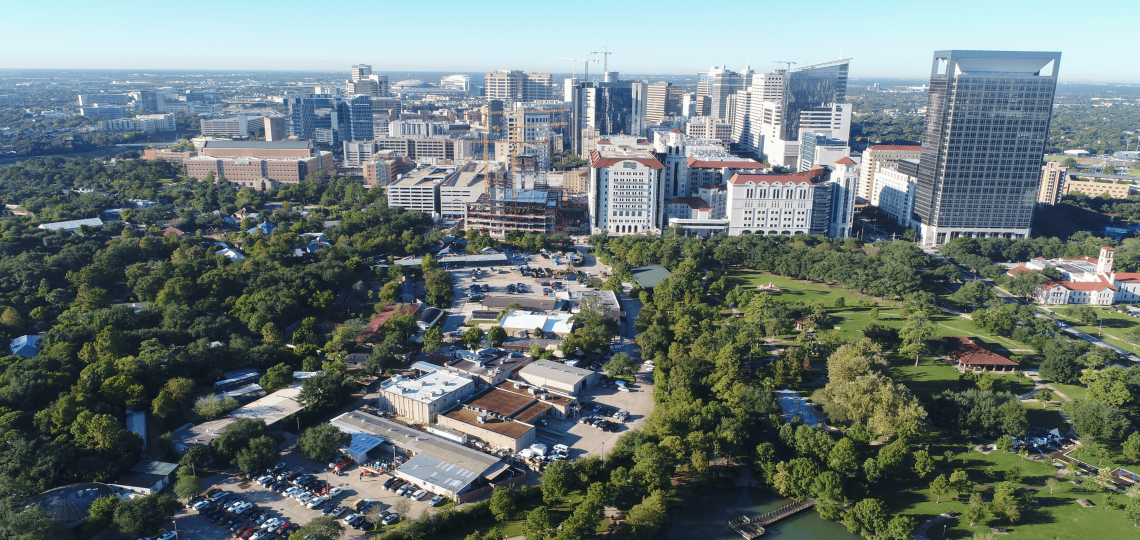 The Texas Medical Center as seen from the sky. Trees flank a row of buildings and parking lots, with taller building seen in the background