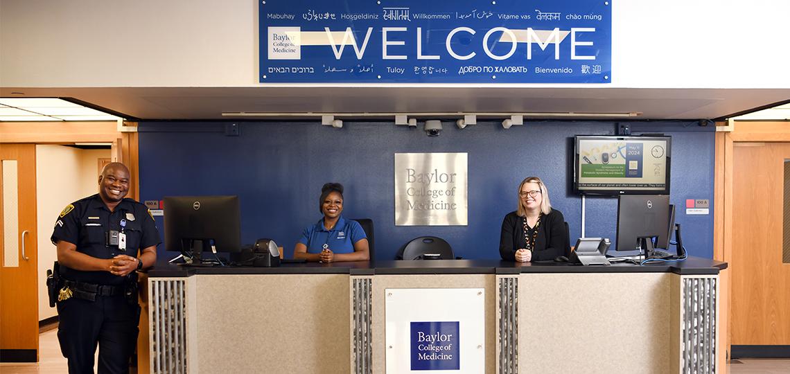 3 people standing at the front desk of a building