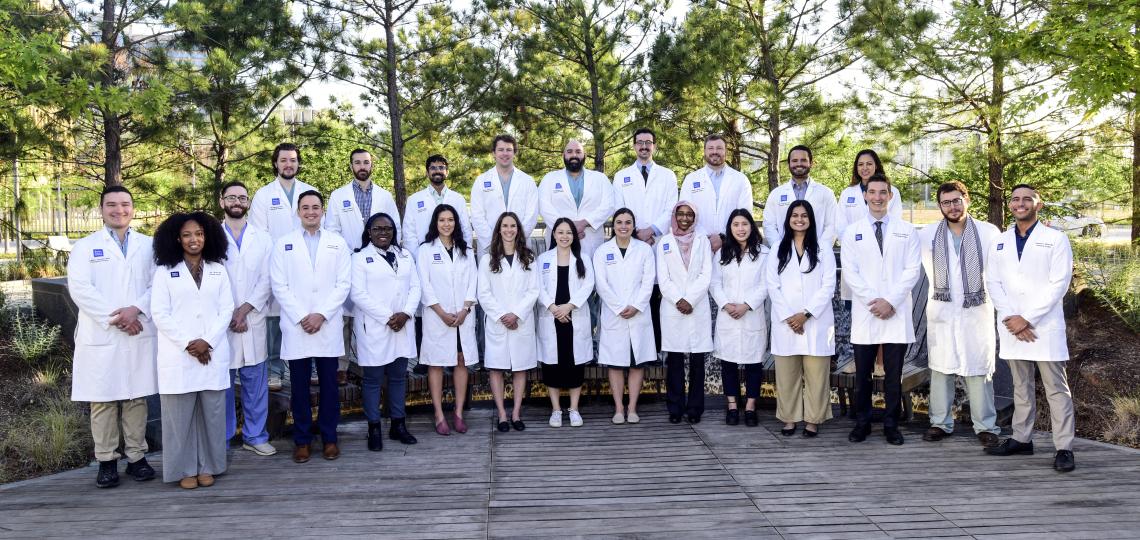 group of doctors wearing white coats smiling outside
