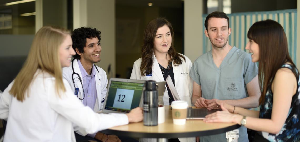 group of people, including doctors, talking at a table