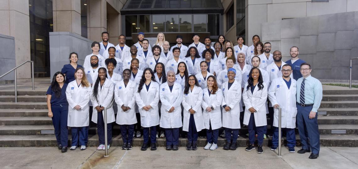 large group of doctors standing on outdoor steps, smiling