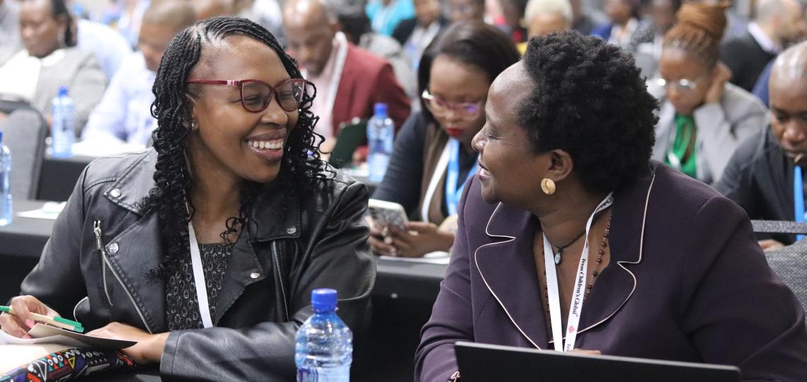 two women smiling at each other at a conference table