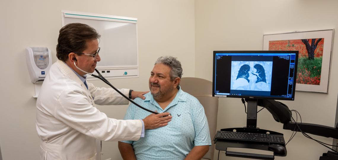 Dr. Ivan Rosas listening to a patient's chest with a stethoscope 