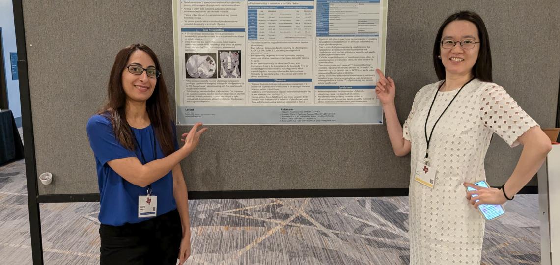 two women smiling and pointing at a poster board