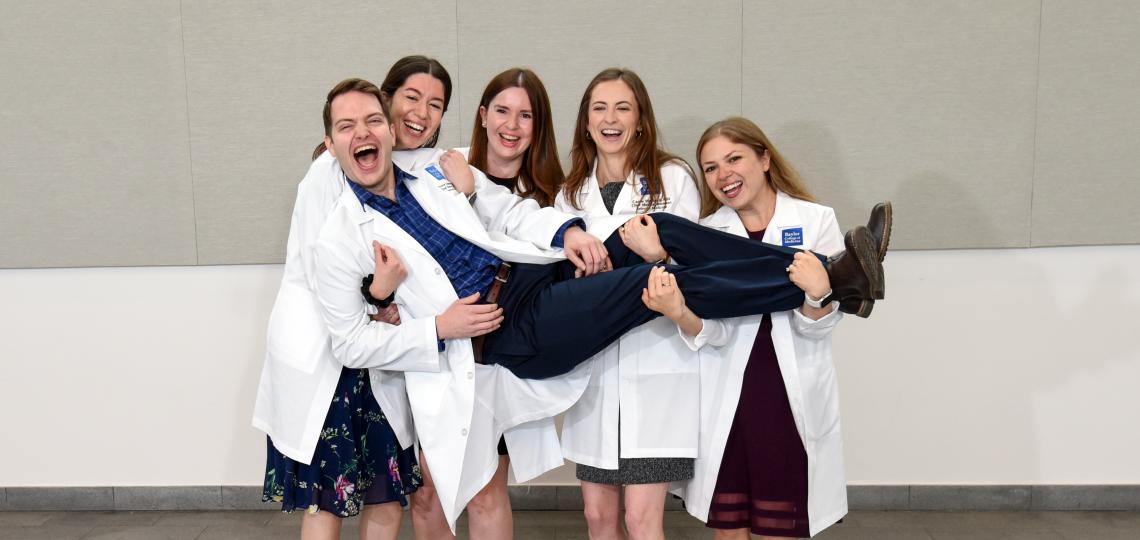 group of people holding one person up and smiling