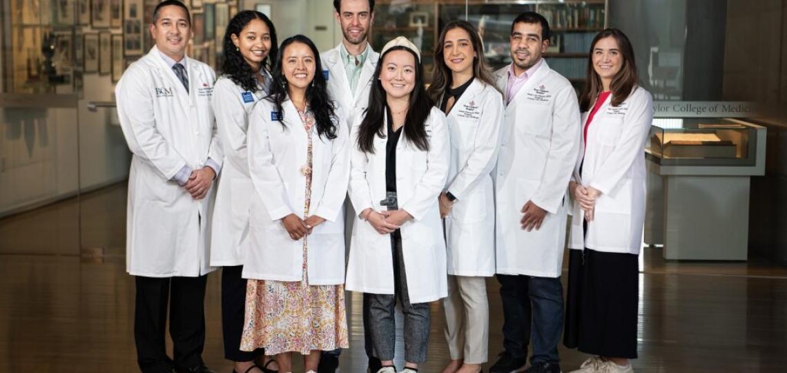 A group of smiling students wearing their white coats.