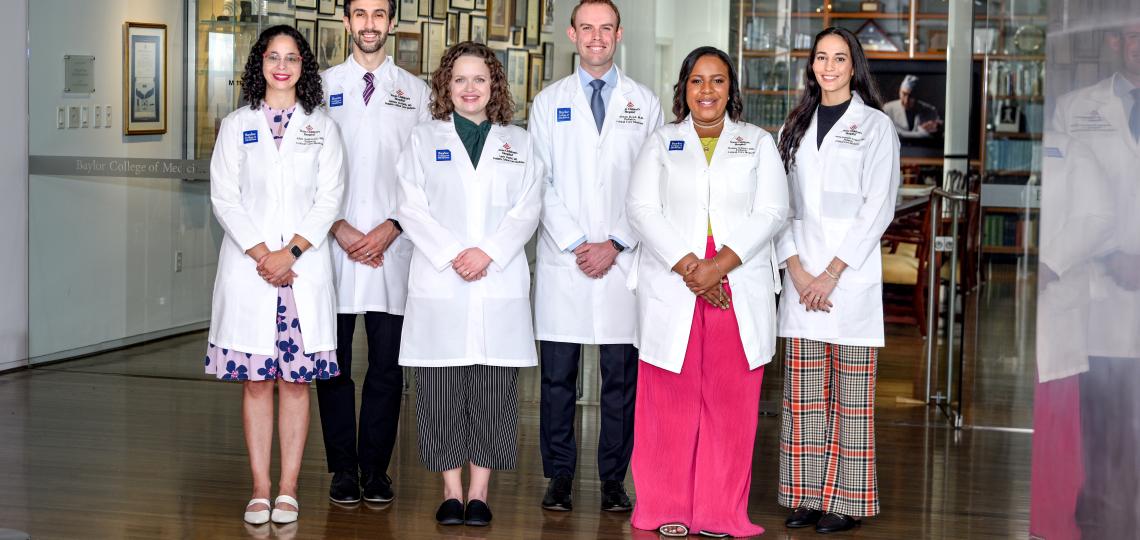 Six students in white coats smiling in a museum