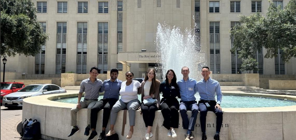 group of people sitting in front of a fountain smiling