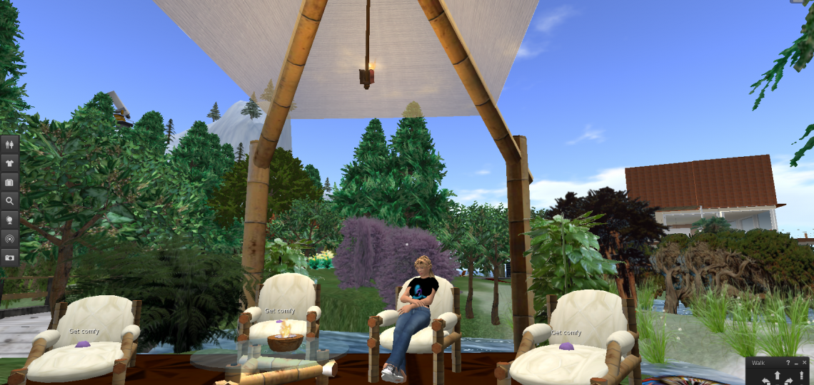 A cartoon image of Dhira sitting in a relaxed pose in a lounge chair under a cabana in a garden by a stream on the CROWD Second Life island