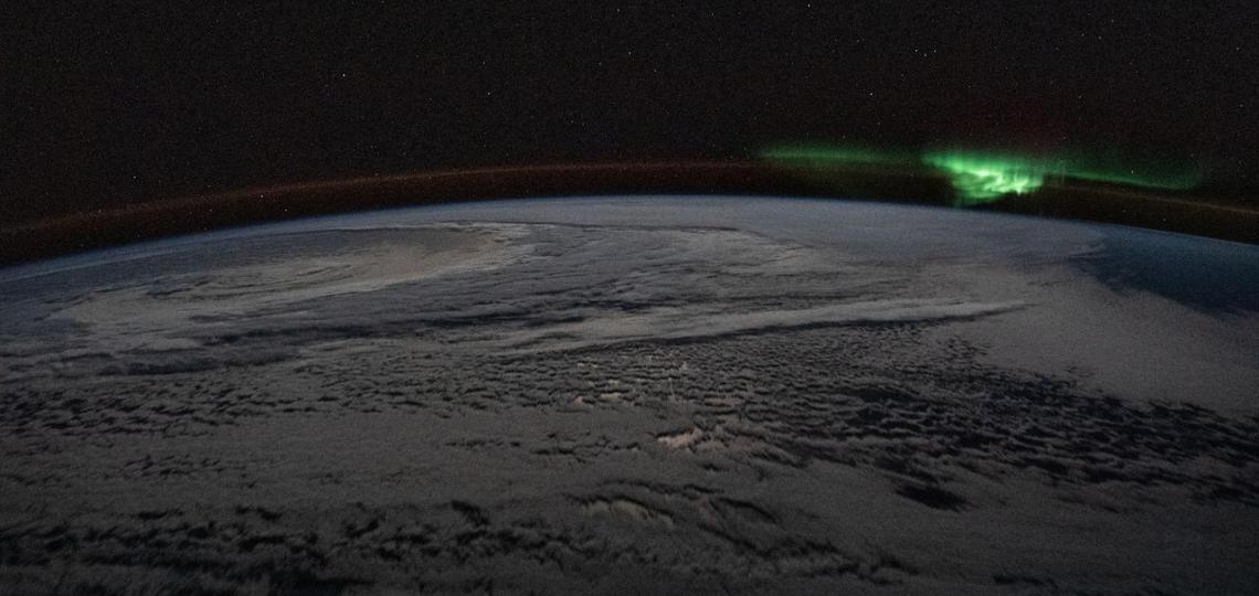 The atmospheric glow and a wispy aurora australis, also known as the "southern lights," frame a cloud-covered Earth as the International Space Station orbited 254 miles above the Indian Ocea.
